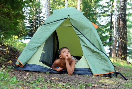 thoughtful boy in forest camping tentの写真素材