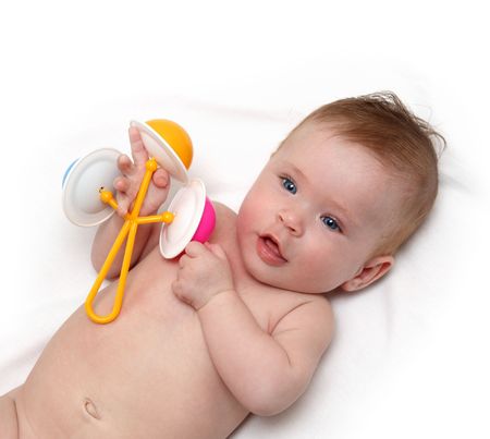 baby girl with rattle on white sheetの写真素材