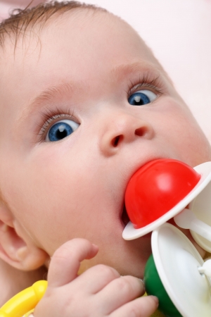 baby girl biting rattle close-up portraitの写真素材