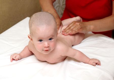 beauty small baby massaging on white sheetの写真素材