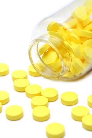 yellow pills and transparent bottle isolated on whiteの写真素材