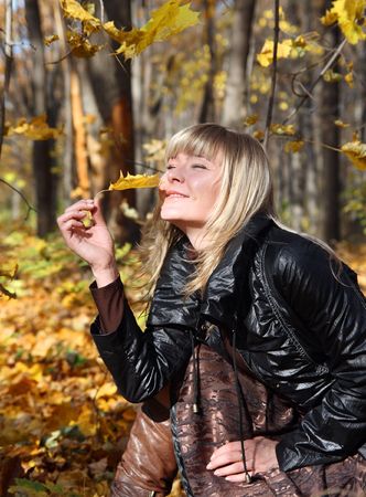 happy young girl with yellow leaf on autumn backgroundの写真素材