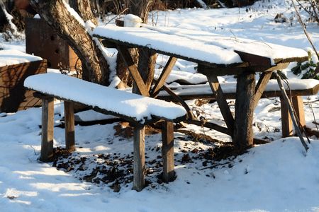 benches and table under snow in winter garden