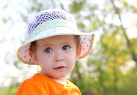 baby in hat and orange dress outdoor portraitの写真素材