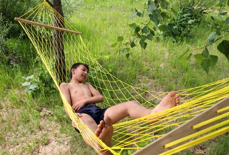 asian boy relaxing in hammock outdoorsの写真素材