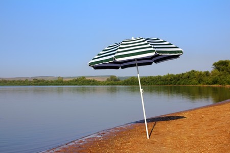 sun umbrella on empty sandy river beachの写真素材