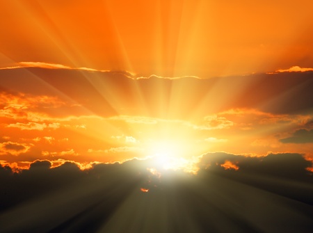 beautiful orange sunset with sunbeams and dark cloudsの写真素材
