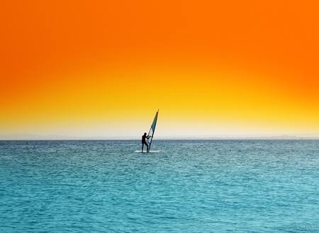windsurfing - surfer on blue sea under orange skyの写真素材