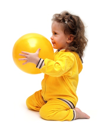 cute little girl in yellow playing with ballの写真素材