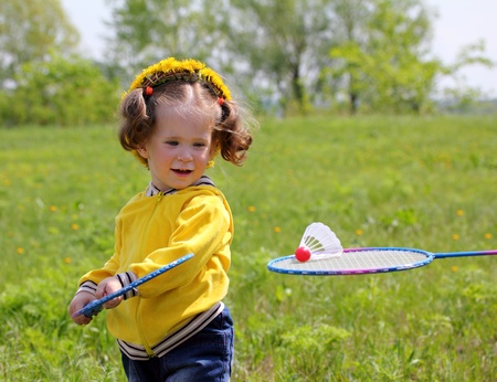 little girl playing badminton on spring meadowの写真素材
