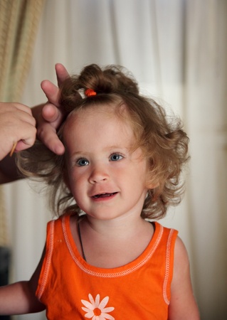 little girl combing hair by motherの写真素材