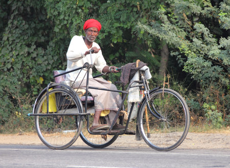 AGRA, INDIA - NOVEMBER 16, 2012: Old indian man on bike with manual drive in Agra, India, 16 nov 2012のeditorial素材