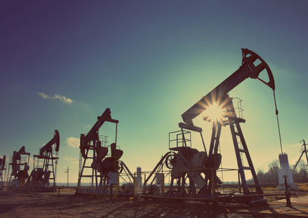 working oil pumps silhouette against sun - vintage retro styleの写真素材
