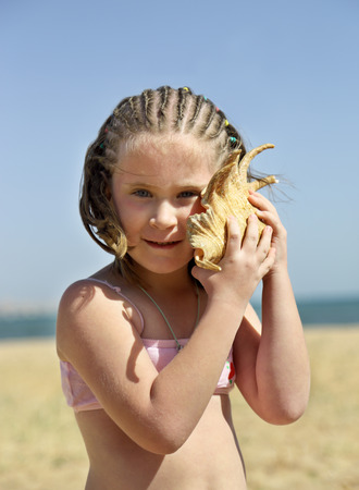 Vacation - listening to the sea - little girl with shell on beach - vintage retro styleの写真素材