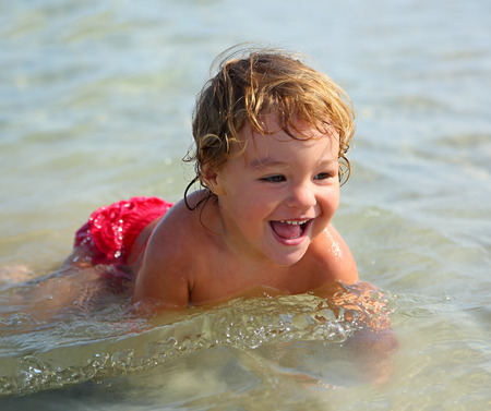 happy child bathing in the sea on the beachの写真素材