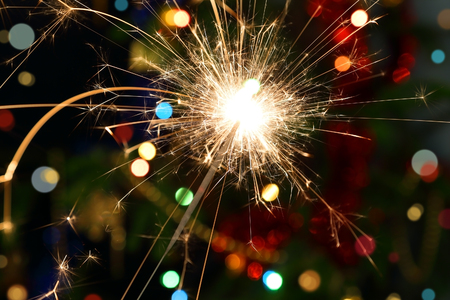 sparkler burning on background decorated Christmas treeの写真素材