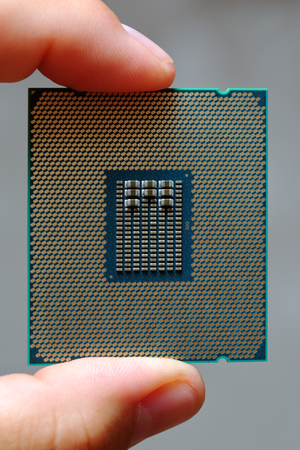 The fingers of man hold a modern central processor unit CPU macro