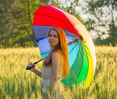 Portrait of a cute girl with a multicolored umbrellaの写真素材