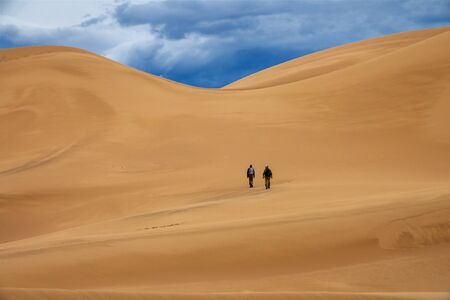 Travelers in desert dunes in mountainsの写真素材