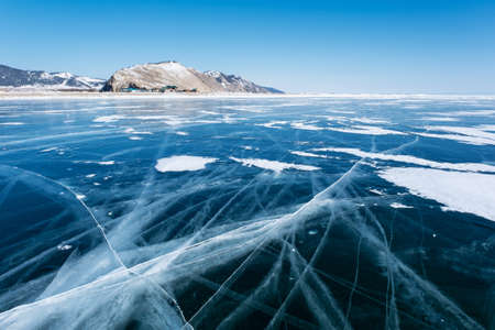 Clear ice on Baikal lake and villageの写真素材