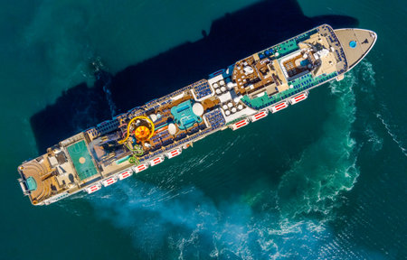 Sailing large cruise ship is unfolding, aerial top viewの写真素材