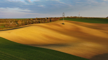 Aerial view of amazing green wavy hills with agricultural fields in evening spring. South Moravia...