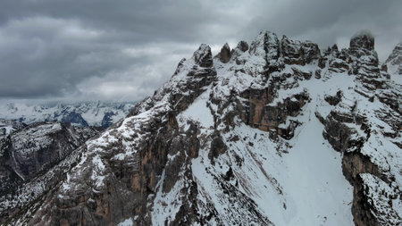 Aerial view of amazing rocky mountains in snow under moody gray clouds, Dolomites, Italyの写真素材