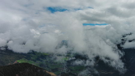 Flying between clouds. Aerial view of snowcapped mountains in clouds, Austrian Alps, Austriaの写真素材