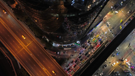 Aerial top view of skycrapper with reflection in glass busy traffic at night in big city, rush hour...