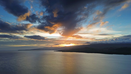 Aerial view of stunning sunset over calm sea waters with vibrant colors illuminating the skyの写真素材