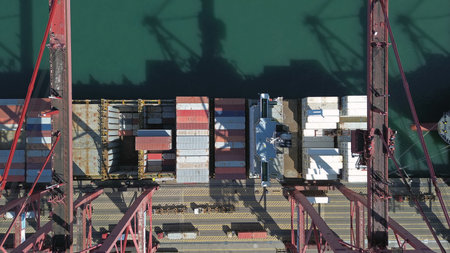 Aerial top view of heavy cargo containers stacked during unloading at a shipping dock in port