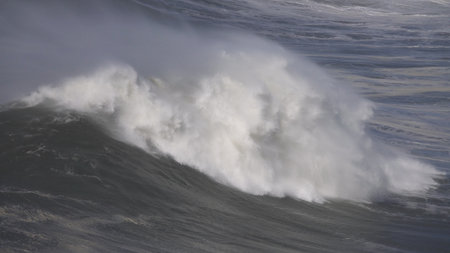 Large foamy wave rolling on the surface of a stormy oceanの写真素材