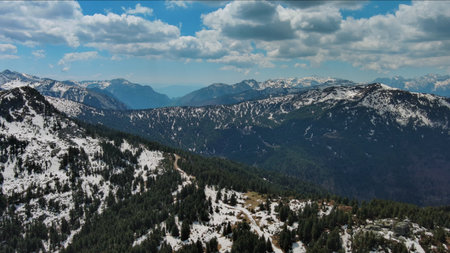 Aerial view of rocky mountains in snow and green fir forest, Prokletie, Montenegro