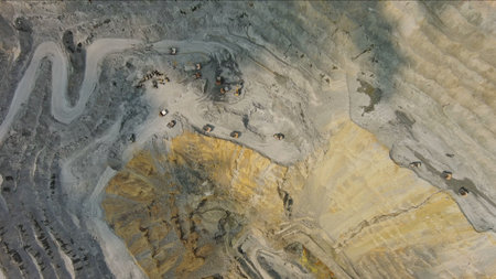Aerial top view of open pit copper ore mine and heavy mining equipment. Excavator and mining trucks...