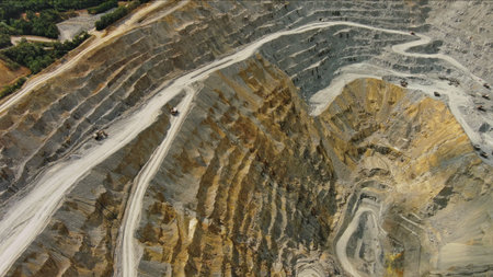 Aerial top view of open pit copper ore mine and heavy mining equipment. Excavator and mining trucks...
