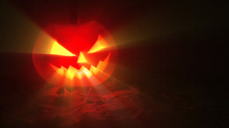 Jack-o-lantern - Halloween pumpkin with candle against a dark background with light rays, in a spooky Halloween conceptの写真素材