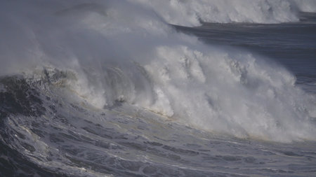 Large foamy wave rolling on the surface of a stormy ocean