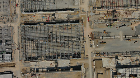 Aerial top view of large industrial construction site with construction equipment and materials