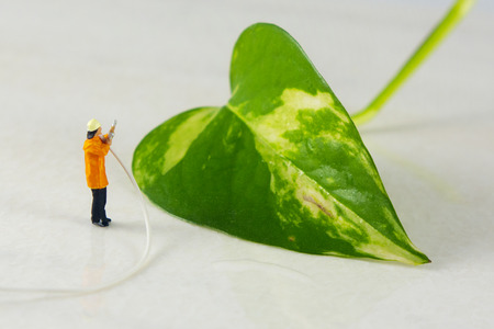 Mini firefighter watering a plantの写真素材
