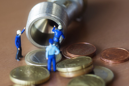 Mini workers repairing pipe losing moneyの写真素材