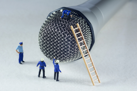 Mini firemen climbing a microphoneの写真素材