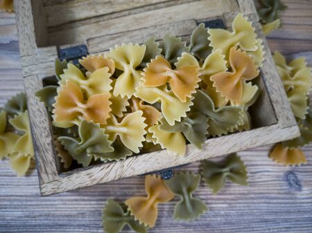 Tricolor farfalle raw pasta and wooden boxの写真素材