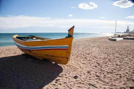 Yellow Boat lying on a sunny beach at the day with sea and white clouds in the backgroundの写真素材