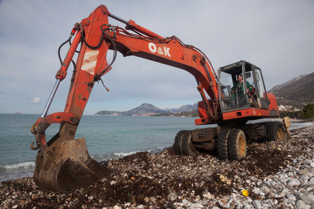 Urban services carried out a public beach cleaning before the tourist season start with the help of red excavatorのeditorial素材