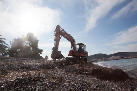 Urban services carried out a public beach cleaning before the tourist season start with the help of red excavatorのeditorial素材