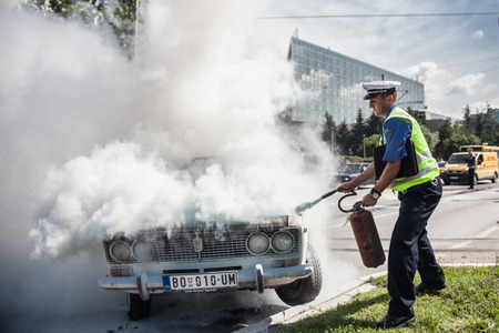 The policeman douses a fire after car ignition accident  at one of crossroads of Belgrad. Serbiaのeditorial素材