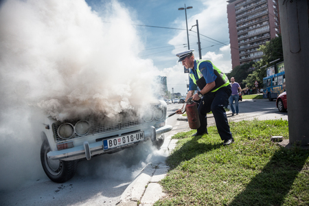 The policeman douses a fire after car ignition accident  at one of crossroads of Belgrad. Serbiaのeditorial素材