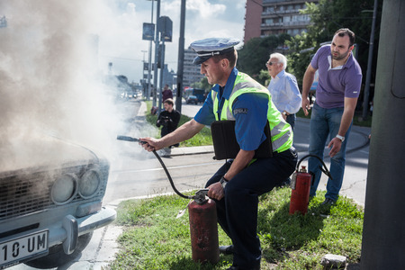 The policeman douses a fire after car ignition accident  at one of crossroads of Belgrad. Serbiaのeditorial素材
