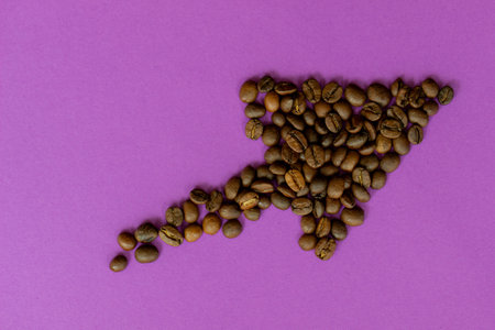 Coffee beans in the shape of an arrow on a purple background