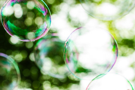 Colorful soap bubbles on green bokeh background with copy space